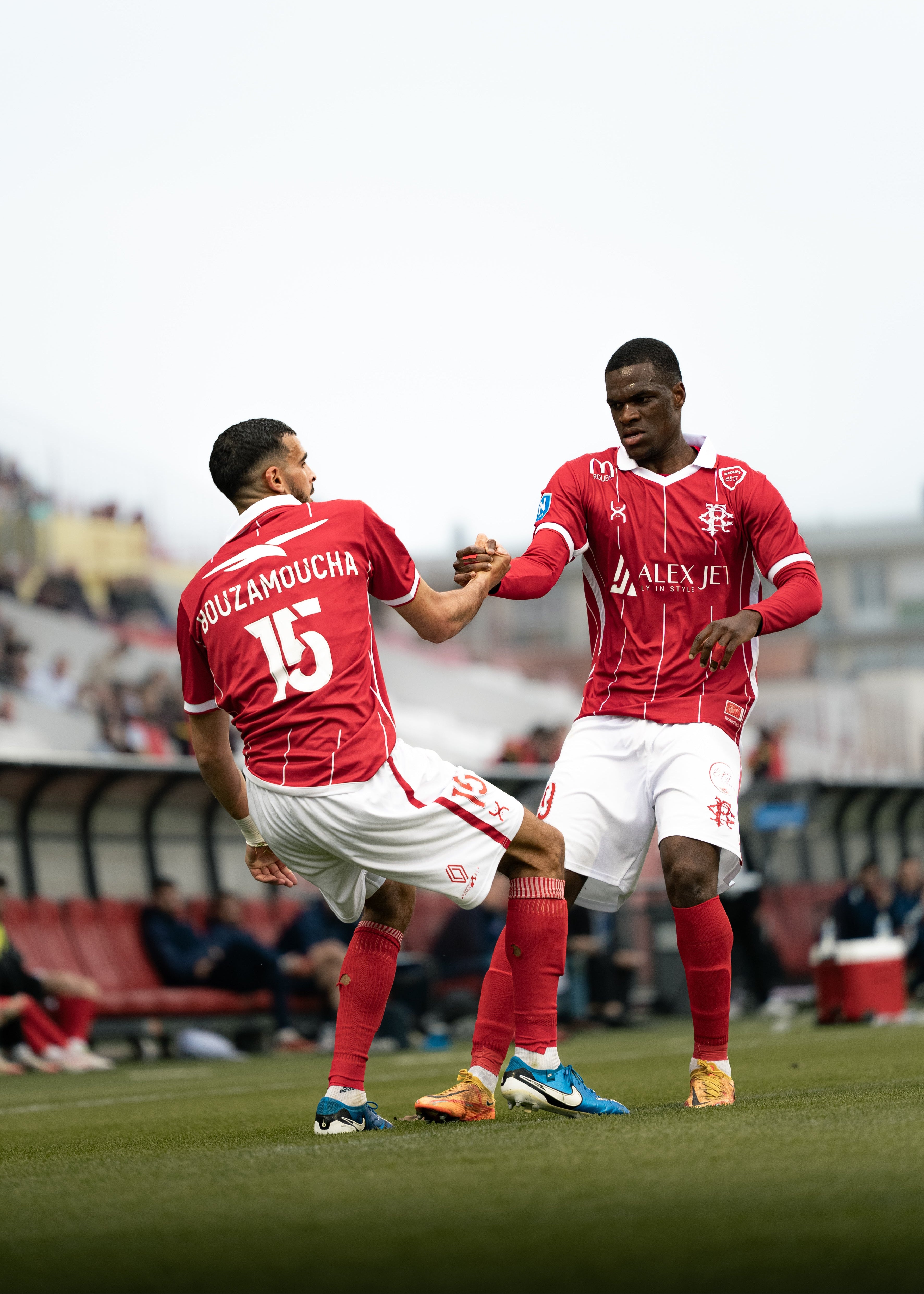 Two soccer players in red jerseys celebrating on a field with a blurred background